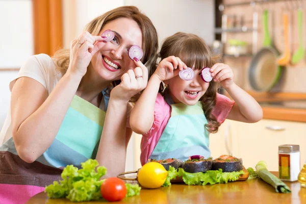 Mother and daughter playing with vegetables in kitchen, healthy food
