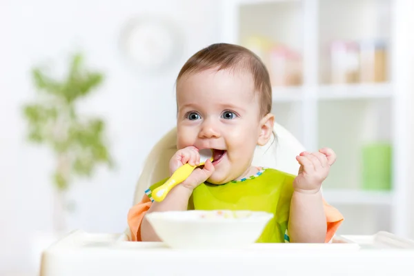 Baby child sitting in chair with a spoon