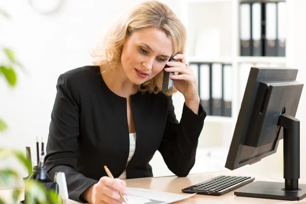 Middle-age business woman talking on the mobile phone in office. Portrait of smiling businesswoman.