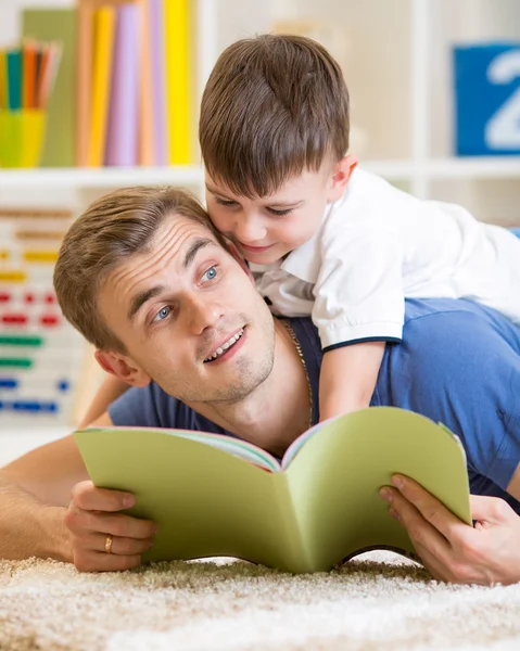 Child boy and father read a book on floor at home