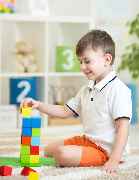 Child boy playing with wooden colorful cubes