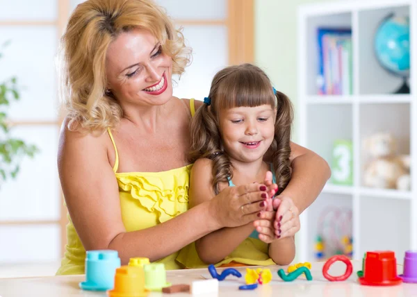Mom and daughter play colorful clay toys at home