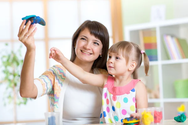 Woman teaches child handcraft at kindergarten or playschool