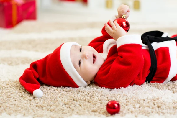 Baby boy weared Santa hollding christmas ball