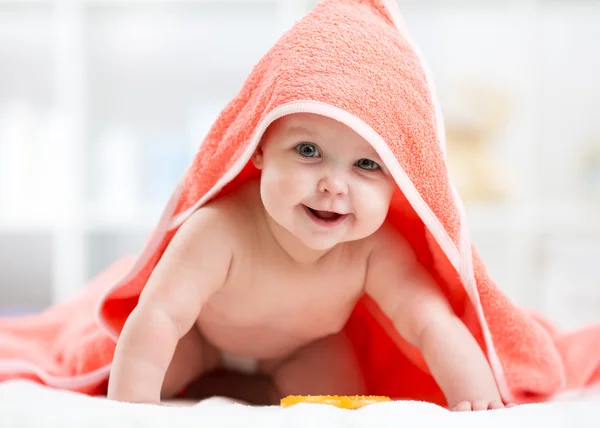 Adorable baby child under a hooded towel after bath