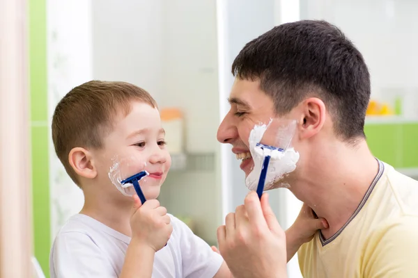 Playful father and son shaving together at home bathroom