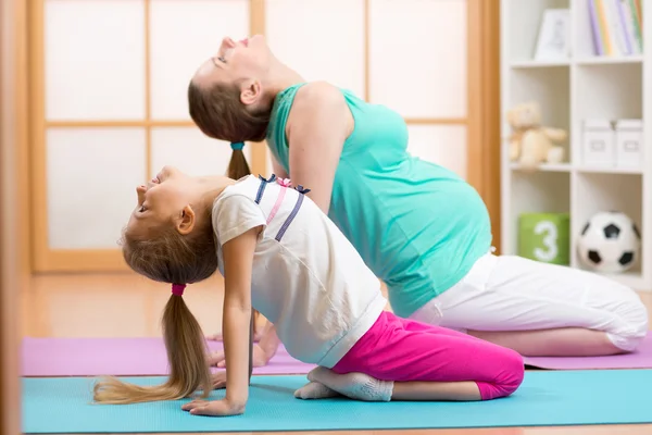 Beautiful pregnant woman with elder child daughter doing gym fitness exercise