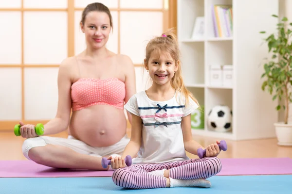 Pregnant woman and her elder child doing fitness exercises  with dumbbells