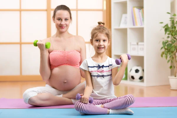 Pregnant mom and elder child engage in fitness dumbbells