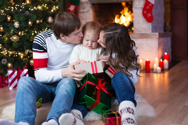 Happy parents kissing little son and giving gifts on Christmas and New Year