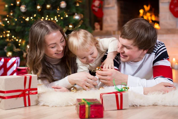 Happy family with kid son have a fun pastime near Christmas tree and fireplace  in living room