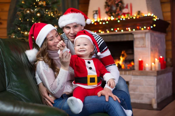 Happy family sitting on sofa near Christmas tree and fireplace  in living room