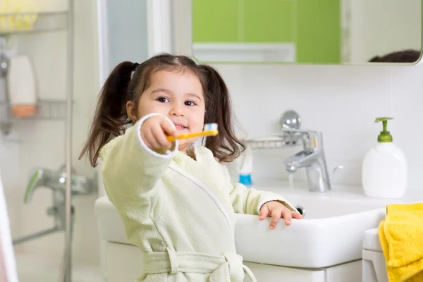 Smiling little girl brushing teeth in bath
