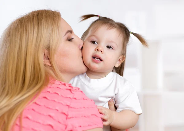 Portrait of beautiful mother kissing her child girl