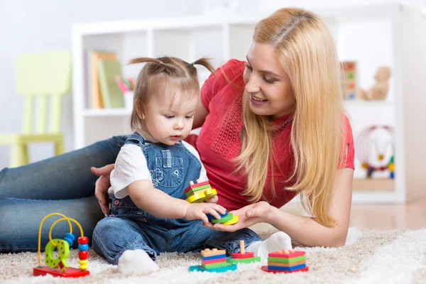 Mother teaches her child to distinguish shape and colur plaing with toys.