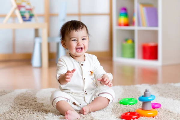 Cute cheerful baby playing with colorful toy at home
