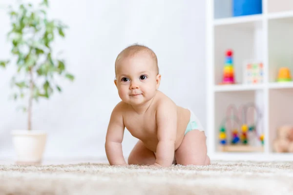 Happy baby child smiling and crawling on floor in nursery