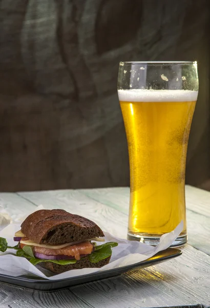 Rye bread sandwich with fish and beer glass