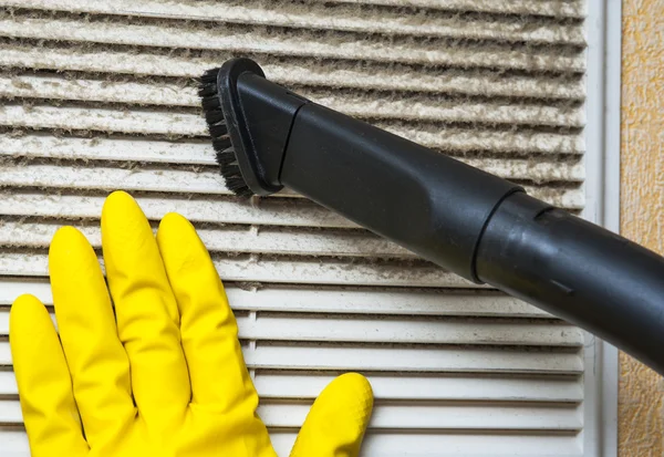 Hand in yellow glove and vacuum cleaner pipe