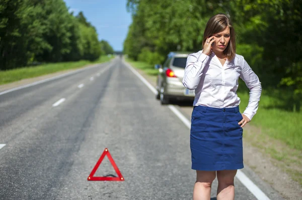 Female driver calling to a car assistance after breakdown