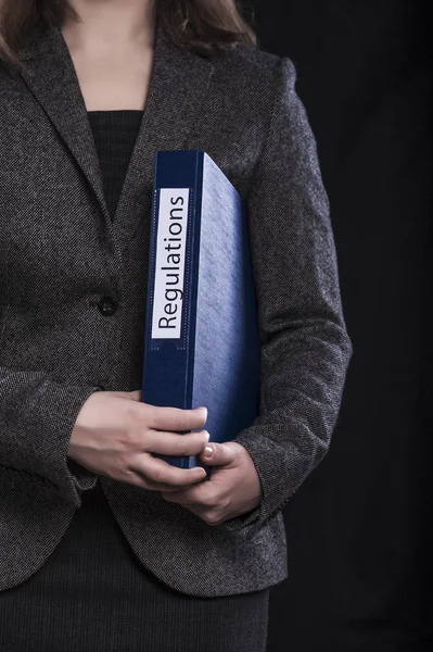 Woman in suit holding folder with inscription Regulations