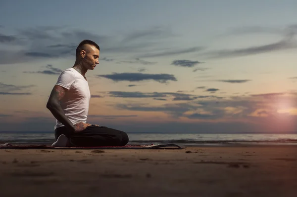 Flexible yoga man meditating on the beach