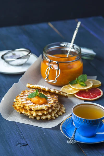 Wafers on baking paper with a jar of persimmon jam