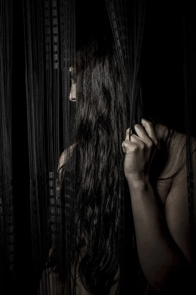 Brunette woman behind a curtain
