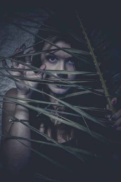 Girl hidden behind the branches of a tree