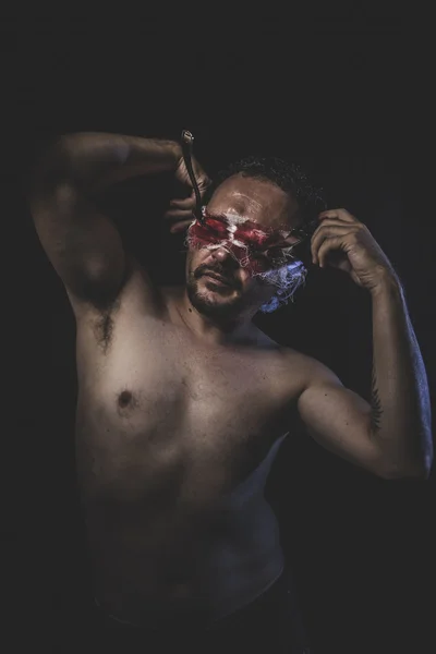 Naked man with blindfold soaked in blood