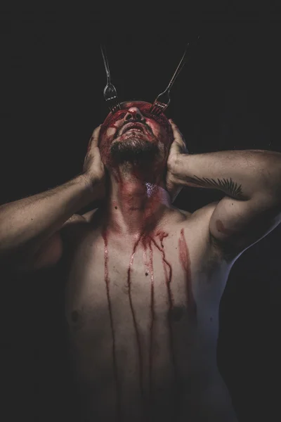 Naked man with blindfold soaked in blood