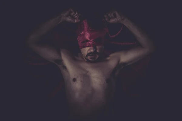 Naked man on red cloth over his eyes