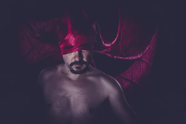 Naked man with red cloth over his eyes