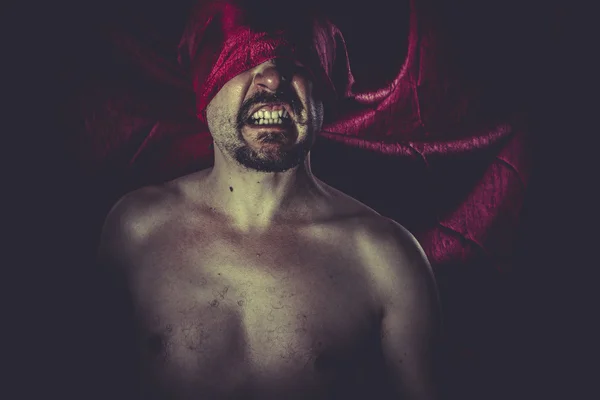 Naked man with red cloth over his eyes
