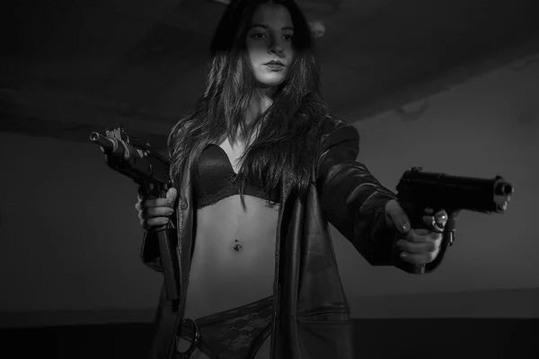 Brunette girl dressed in black leather with guns and pistols in