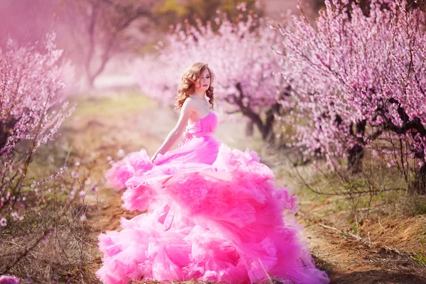 Beautiful girl in a pink dress in peach garden