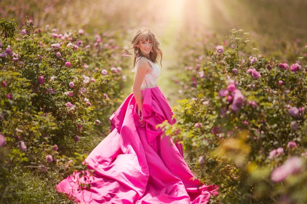Beautiful girl dancing in a field of roses