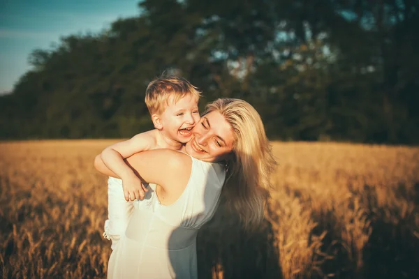 Mom and son having fun by the lake, field outdoors enjoying nature. Silhouettes on sunny sky. Warm filter and film effect