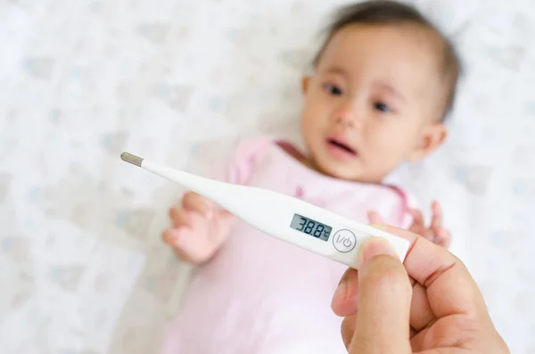 Measuring Asian baby temperature with digital thermometer