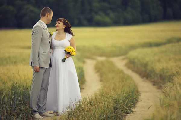 Bride and groom walking on wheat field