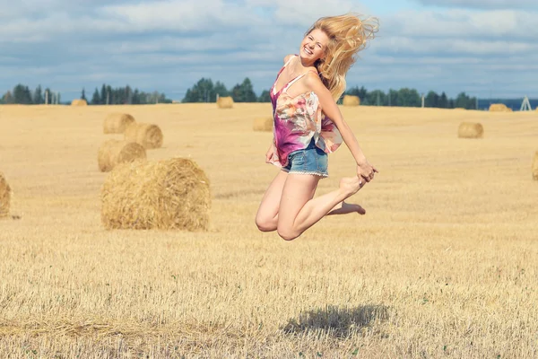 Blonde woman jumps in field