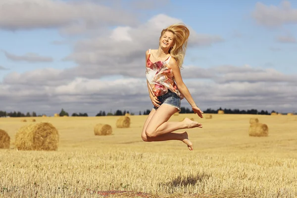 Blonde woman jumps in field