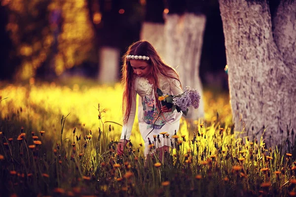 Girl collects flowers in sunny park