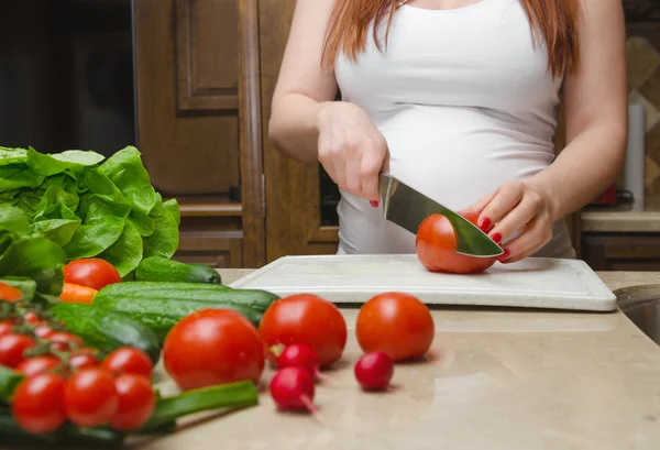 Pregnant woman cut fresh vegetables for salat close up