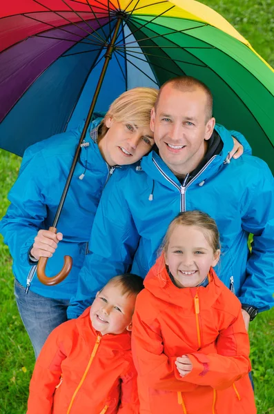 Happy rain family  under colorful umbrella