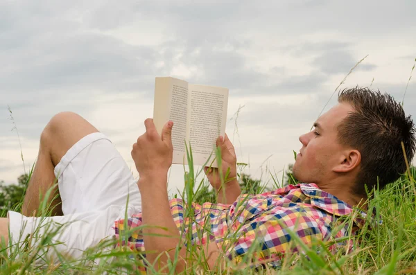 Man reading a book lying in the grass