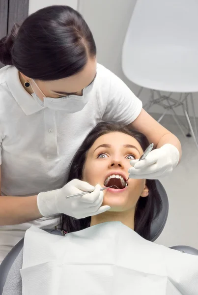 Woman in the dentist\'s chair is looking frightened