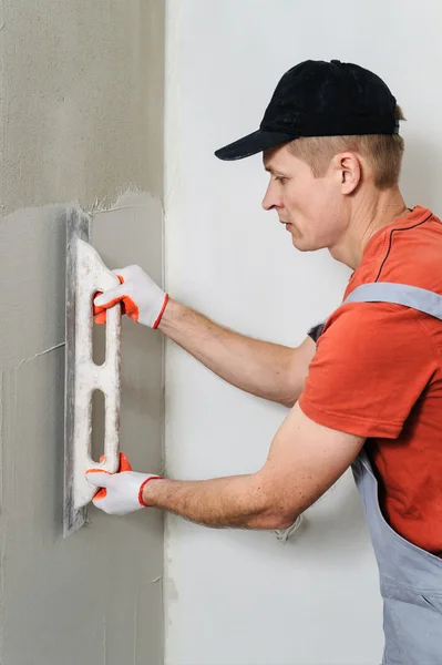 The worker puts the stucco on the wall