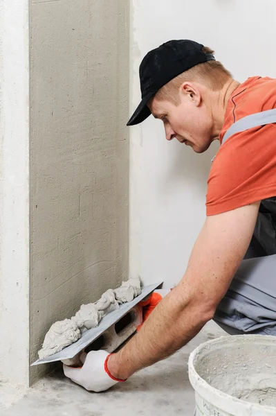 The worker puts the stucco on the wall