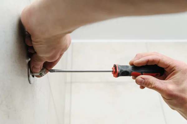 Worker uses a screwdriver.
